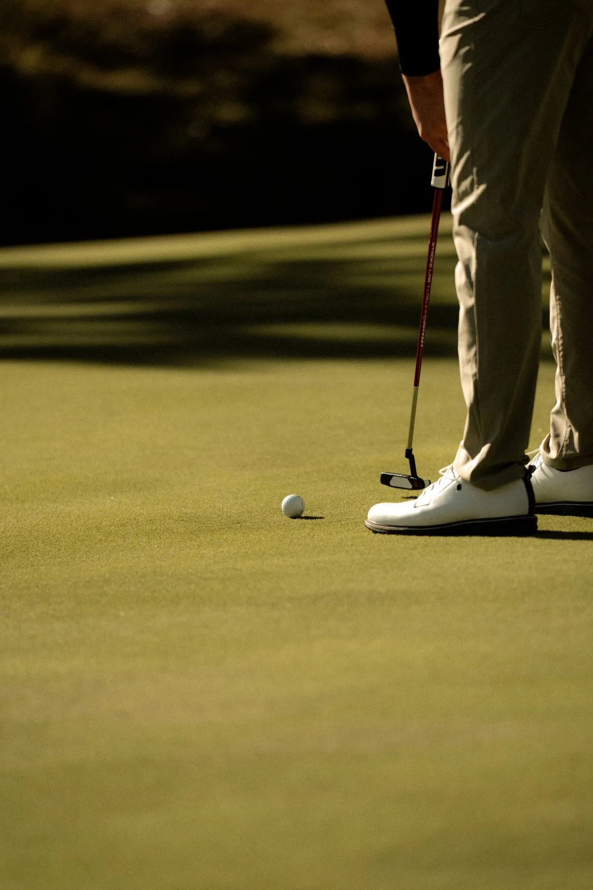 A golfer lining up a putt on a sunlit green